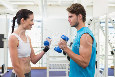 Fit smiling couple exercising with blue dumbbells