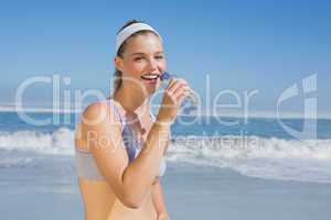 Sporty happy blonde drinking water on the beach