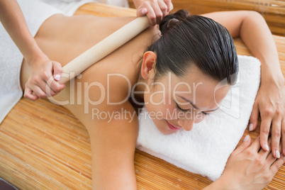 Smiling brunette getting a bamboo massage