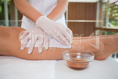 Woman getting her legs waxed by beauty therapist