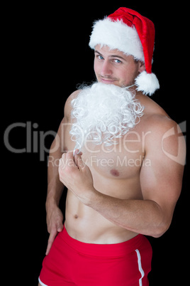 Smiling muscular man posing in sexy santa outfit with fake beard