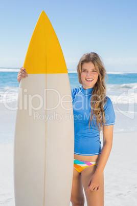 Fit smiling surfer girl on the beach with her surfboard