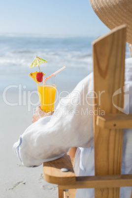 Woman relaxing in deck chair by the sea holding cocktail