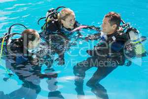 Smiling friends on scuba training in swimming pool