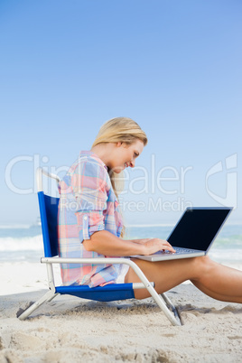 Woman sitting on beach using her laptop