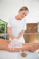 Woman getting her legs waxed by beauty therapist