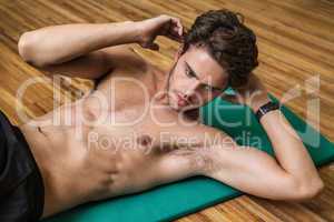 Fit shirtless man doing sit ups in fitness studio