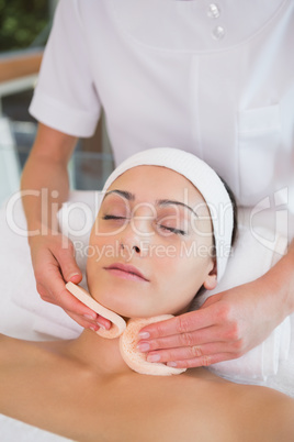 Peaceful brunette getting facial from beauty therapist