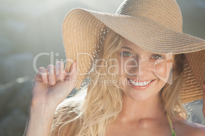 Gorgeous blonde in straw hat smiling at camera on beach