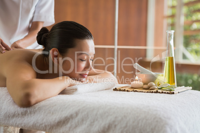 Brunette enjoying a massage with beauty treatments beside