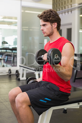 Fit man lifting heavy black dumbbells