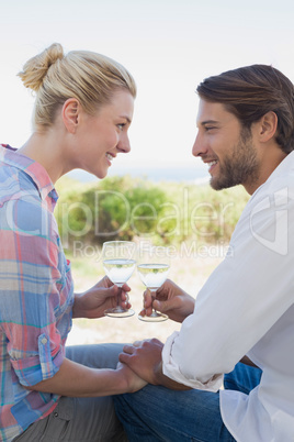 Happy young couple sitting in the garden enjoying wine together
