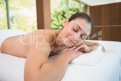 Beautiful brunette lying on massage table with eyes closed