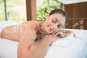 Beautiful brunette lying on massage table with eyes closed