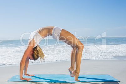 Gorgeous fit blonde in crab pose on the beach