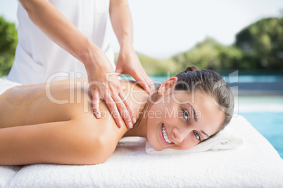 Happy brunette getting a massage poolside