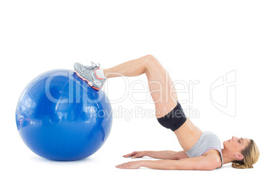 Fit woman lying on floor with legs on exercise ball