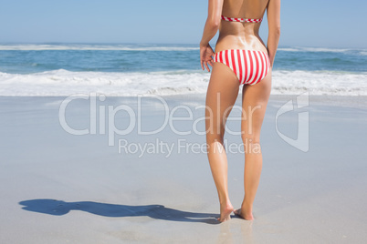 Mid section rear view of fit woman in striped bikini at beach