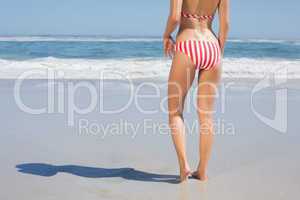 Mid section rear view of fit woman in striped bikini at beach