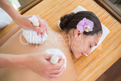 Smiling woman getting a back massage with herbal compresses
