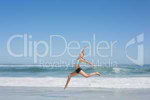 Fit woman jumping gracefully on the beach