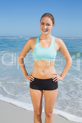 Fit woman standing on the beach with hands on hips