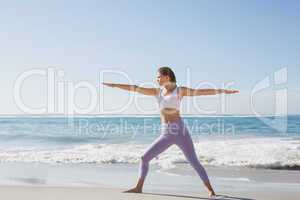 Sporty blonde in warrior pose on the beach