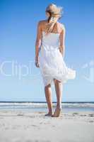 Blonde in white dress strolling on the beach