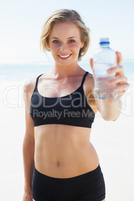 Fit blonde drinking water on the beach