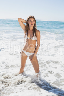 Beautiful smiling woman in white bikini standing on the beach