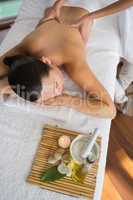 Brunette enjoying a massage with beauty treatments beside