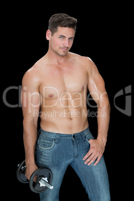 Muscular man holding large dumbbell in blue jeans