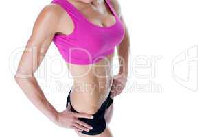 Female bodybuilder posing in pink sports bra mid section