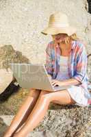 Pretty blonde using laptop at the beach