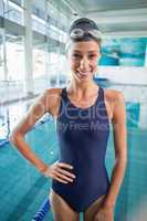 Pretty swimmer standing by the pool smiling at camera