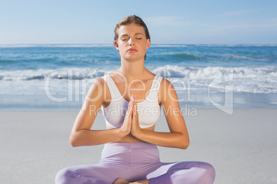 Sporty blonde sitting in lotus pose on the beach