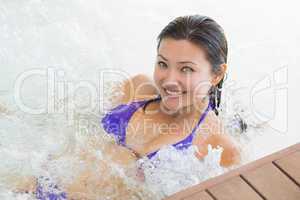 Smiling brunette in bikini relaxing in hot tub