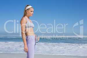 Sporty blonde standing on the beach with water bottle