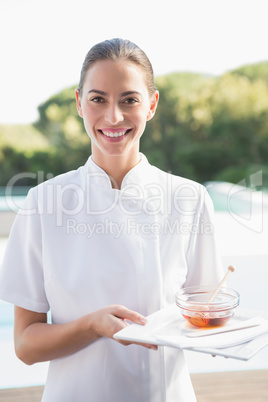 Smiling beauty therapist looking at camera holding plate with ho