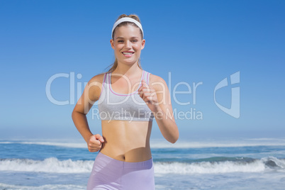 Sporty happy blonde jogging on the beach