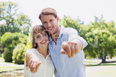 Cute couple pointing to the camera in the park