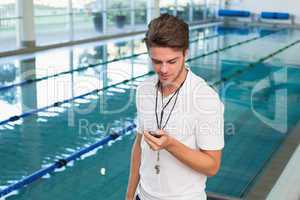 Swimming coach looking at his stopwatch by the pool