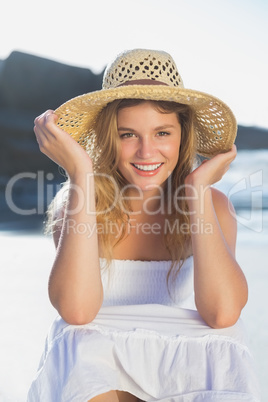 Beautiful smiling blonde in sundress sitting on the beach