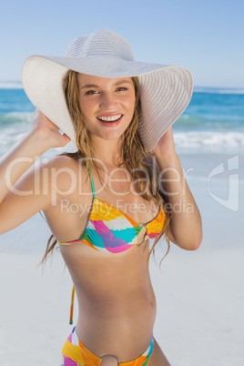 Beautiful girl in bikini and straw hat on the beach smiling at c