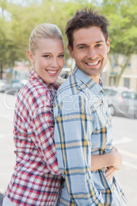 Young hip couple standing and hugging smiling at camera