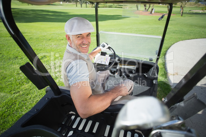 Happy golfer driving his golf buggy smiling at camera