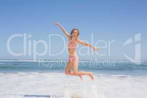 Happy fit woman in bikini jumping on the beach