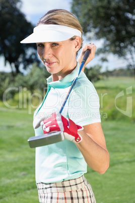 Female golfer standing holding her club smiling at camera