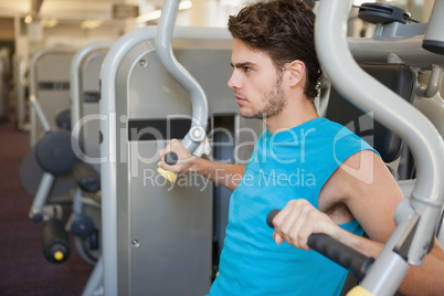 Focused man using weights machine for arms