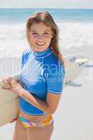 Fit smiling surfer girl on the beach with her surfboard